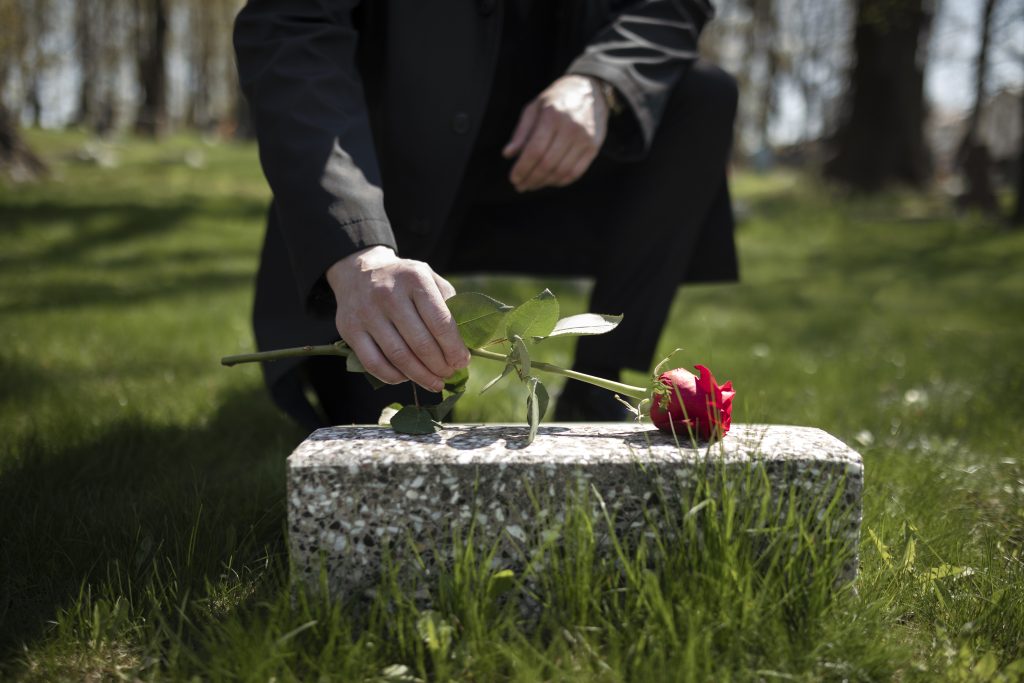 man bringing rose tombstone cemetery