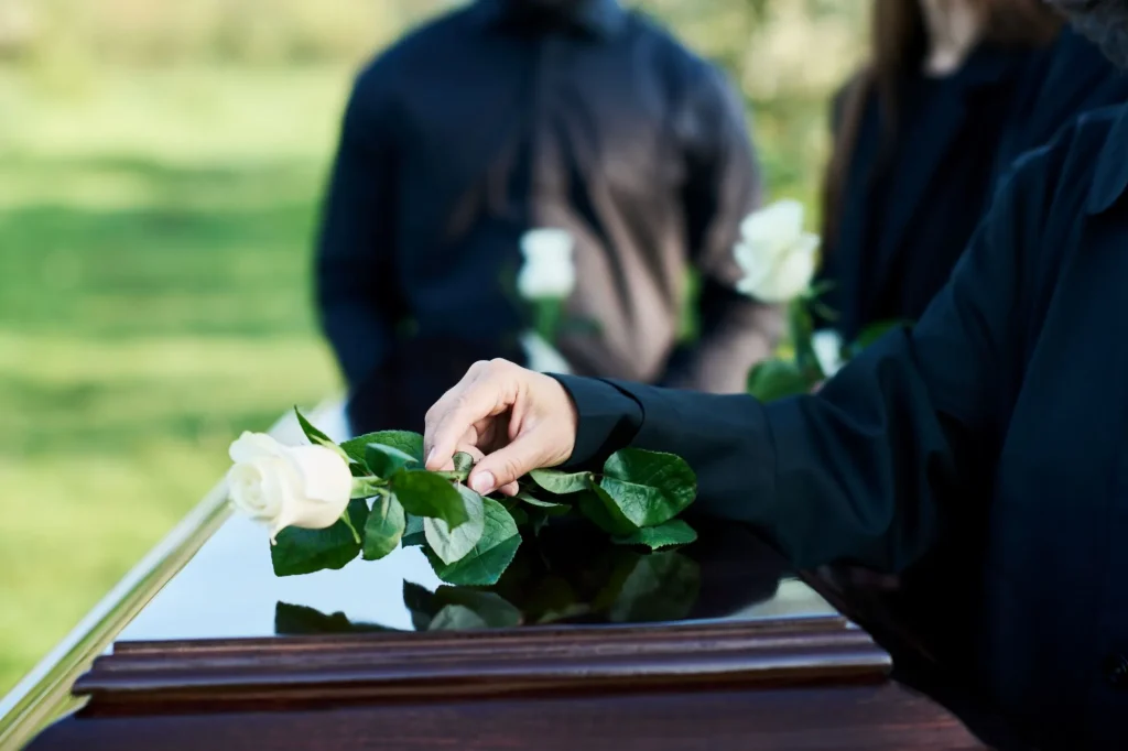 finalexpensequoter.com hand mature woman mourning attire putting white rose coffin